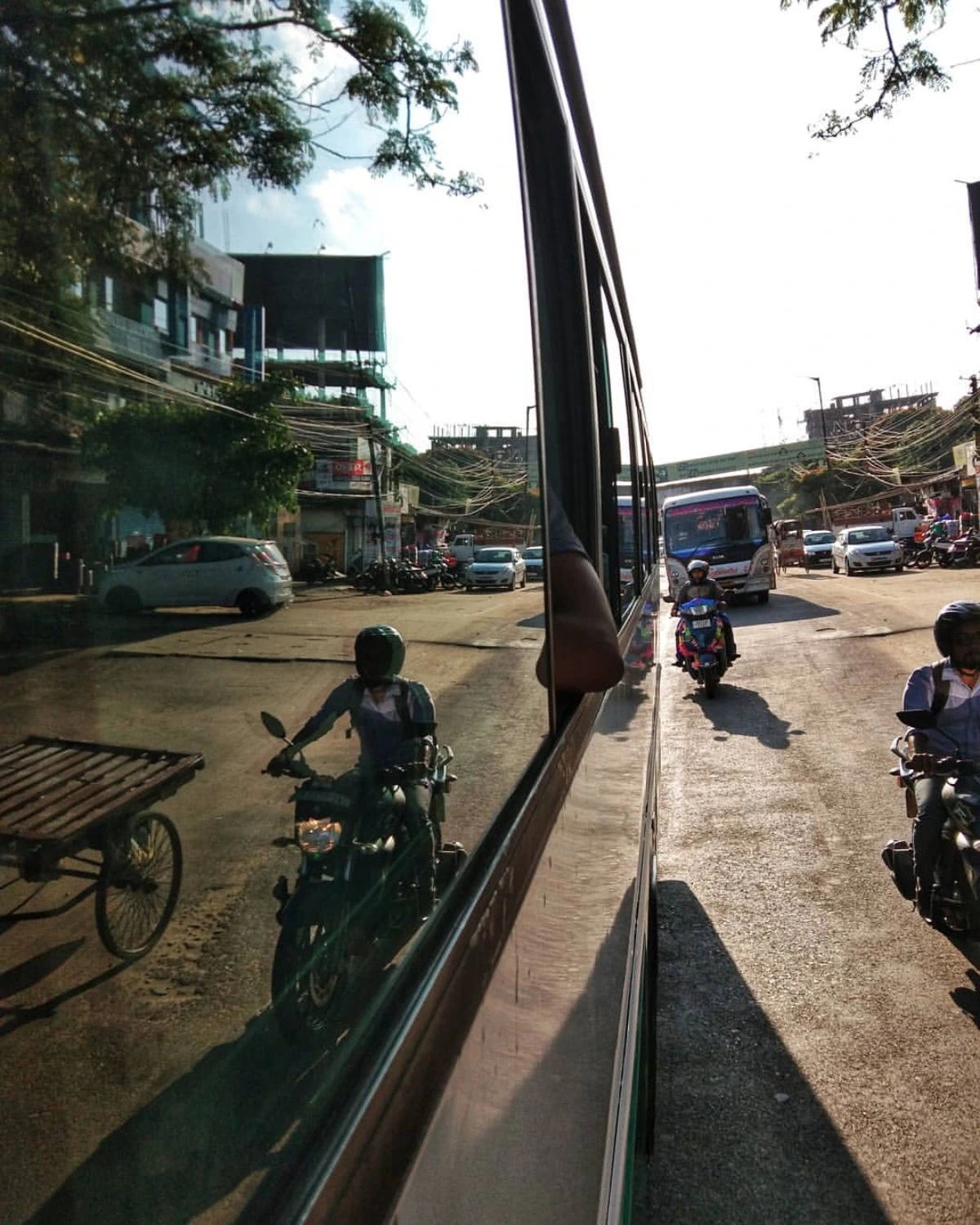 Traffic on an Indian street reflected in the window of a moving bus